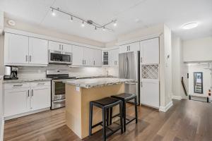 a kitchen with white cabinets and a counter with stools at Blue Mountain Haus - Private Patio - Walk to Blue in Blue Mountains