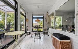 a screened porch with tables and chairs and windows at 2 Bedroom Gorgeous Home In Holbæk in Holbæk