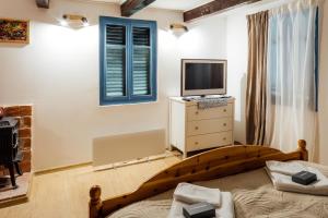 a bedroom with a bed and a television on a dresser at Legatum Cottage 