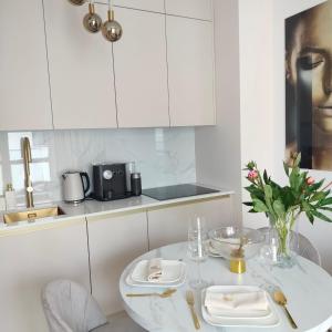 a white kitchen with a white table and a sink at Apartament Echo Park in Olecko