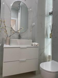 a white bathroom with a sink and a mirror at Apartament Echo Park in Olecko +8 photos