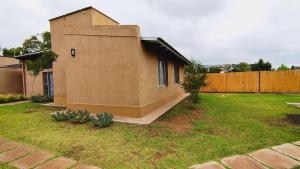 a small brick house with a grass yard at La Isolina Chacras, jardín, parrilla y naturaleza! in Chacras de Coria