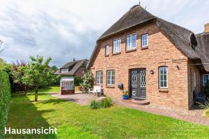 une vieille maison en briques avec un toit de chaume dans l'établissement Wattkieker, à Utersum