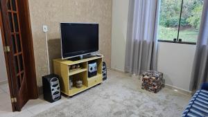 una televisione su un supporto in soggiorno di Casa Completa com Varanda Garagem Wi fi Suíte a São João del Rei