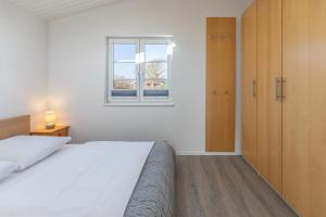 a white bedroom with a bed and a window at Schimmelreiter in Simonsberg