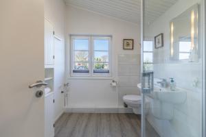 a white bathroom with a toilet and a sink at Schimmelreiter in Simonsberg +23 photos