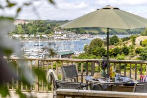a table and chairs with an umbrella on a balcony at River Retreat in Kingswear