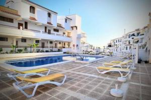 a hotel with a swimming pool and lounge chairs at Joy & Friends 1 in Los Cristianos