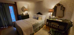 a bedroom with a bed and a mirror and a desk at Carriage Barn Inn in Keene
