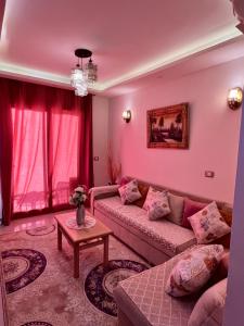 un soggiorno con pareti rosa e divano di Porto Golf -Sia Lagoon-الساحل الشمالي -العلمين a El Alamein