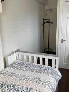 a white bed with a blue and white blanket on it at Studio Flat in Walsall with Option of Large Garden for Events in Bloxwich