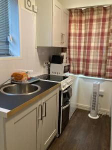 a kitchen with a sink and a stove top oven at Studio Flat in Walsall with Option of Large Garden for Events in Bloxwich