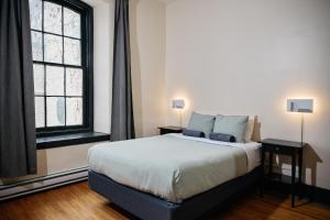 a bedroom with a bed and two windows at Saintlo Ottawa Jail Hostel in Ottawa