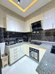 een keuken met witte kasten en een kookplaat oven bij Oaksvale Homes in Enugu +10 foto's