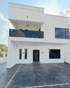 een wit gebouw met een zwarte deur op een parkeerplaats bij Oaksvale Homes in Enugu