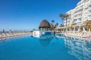 a swimming pool at a resort with chairs and a building at Princess Taurito in Taurito