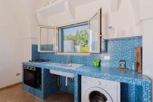 a blue tiled kitchen with a sink and a washing machine at Casa Vacanza Plautilla - Salento Selection in Maglie
