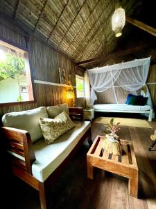 a living room with a couch and a bed and a table at Bungalow à louer AVEC CUISINE ÉQUIPÉE sur plage privée , RAVENALA in Ile aux Nattes +25 photos