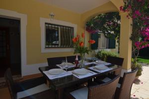 una mesa de comedor con sillas y flores. en Bonita, en Quarteira