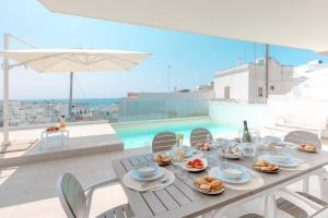 a table with food on top of a balcony with a pool at Radiluxe - Suite Meliso in Leuca