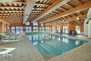 a large swimming pool in a large building at ARC 1950, Appartement 2 chambres, 6 personnes, Exposition Sud, SAUNA, HAMMAM, JACUZZI, PISCINE in Arc 1950