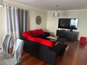 a living room with a red couch and a television at Sea View Andrade 3 Bedroom House in Gaula