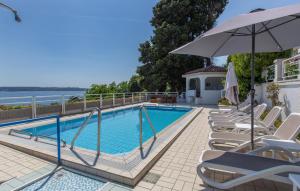 a swimming pool with lounge chairs and an umbrella at 2 Bedroom Amazing Apartment In Portoroz in Portorož +12 photos