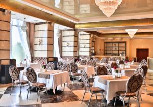 un ristorante con tavoli e sedie bianchi in una stanza di Ukraine Hotel a Kiev