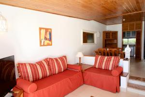 a living room with a red couch and a dining room at Apartamentos Tio Papel in Albufeira