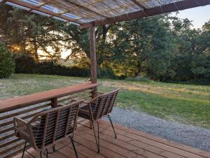 two chairs sitting on a wooden deck with a pergola at Tranquillity in a modern unit in Bazugues