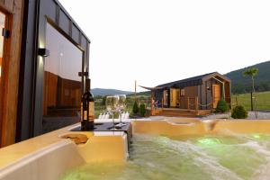 a hot tub with wine glasses and a bottle of wine at Magiczny Widok Tiny House in Jurków