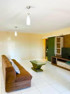 a living room with a couch and a television at Casa Atalaia Paraíso in Atalaia