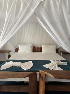 a bed with a canopy with two towels on it at Ekoa Bangalô in Marau