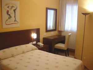 1 dormitorio con cama, escritorio y silla en Hostal Acanto, en Burgos