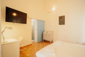 Camera bianca con scrivania e TV a parete. di Casa da avó Bia a Faro