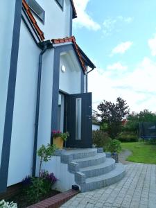 a small white house with a black door at Pokoje nad jeziorem Gdańsk in Gdańsk