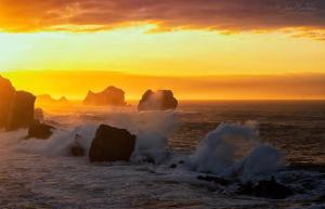 a sunset over the ocean with rocks in the water at Apartamento Costa Quebrada in Liencres