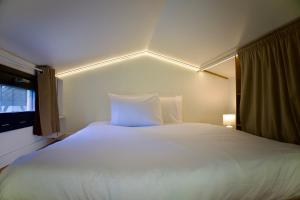 ein großes weißes Bett in einem Zimmer mit Fenster in der Unterkunft La Tiny House des Montagnes in Verrens-Arvey