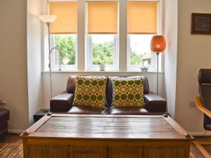 un canapé assis dans un salon avec des fenêtres dans l'établissement Mussel Cottage, à Middleton-on-Sea