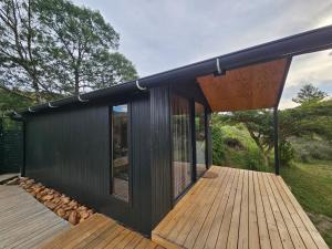 ein schwarzes Haus mit einer Holzterrasse in der Unterkunft Fish Eagle River Camp in Vosburg + 13 Fotos