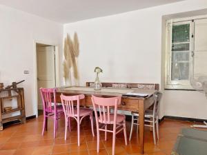 a dining room with pink chairs around a wooden table at La casa con giardino, vicino al ruscello segreto in Borzonasca
