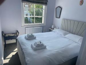 a bedroom with a white bed with towels on it at Stylish Flat B in London