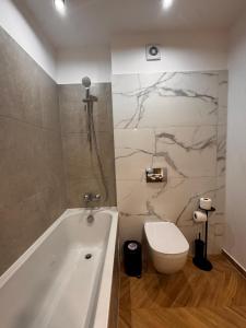 un bagno con vasca, WC e lavandino di MOOS Aparthotel Qualis a Braşov