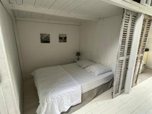 a white bedroom with a bed in a room at Cabine du Capitaine 5 in Fécamp