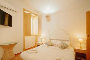 una camera da letto con un letto bianco e una finestra di Casa da avó Bia a Faro