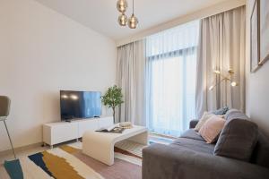 a living room with a couch and a tv at Stylish 1BR Warm & Curated Interiors in Dubai