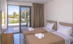 a hotel room with two beds and a balcony at Phoenix Coastal Heaven in Loutro