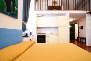 a bedroom with a yellow bed and a kitchen at Residence La Contessina in Florence