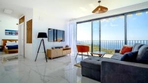 a living room with a couch and a television at CASA PANORAMA SOL- NEW VILLA WITH HEATED SALTWATER POOL and FANTASTIC SEA VIEW in Ponta do Sol +29 photos