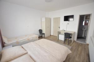 a bedroom with a bed and a desk with chairs at Cris & Mona in Săpânța